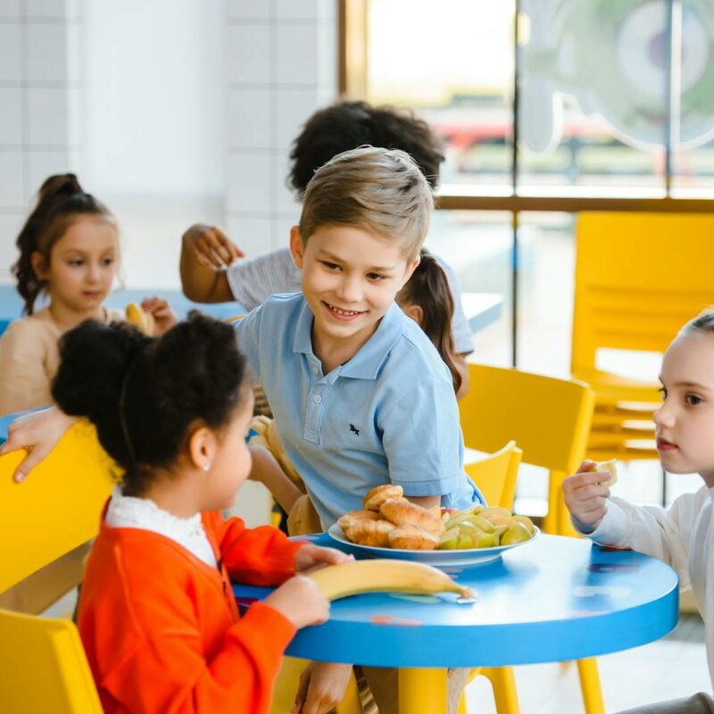 Group of cheerful kids enjoying lunch together in a bright school cafeteria.